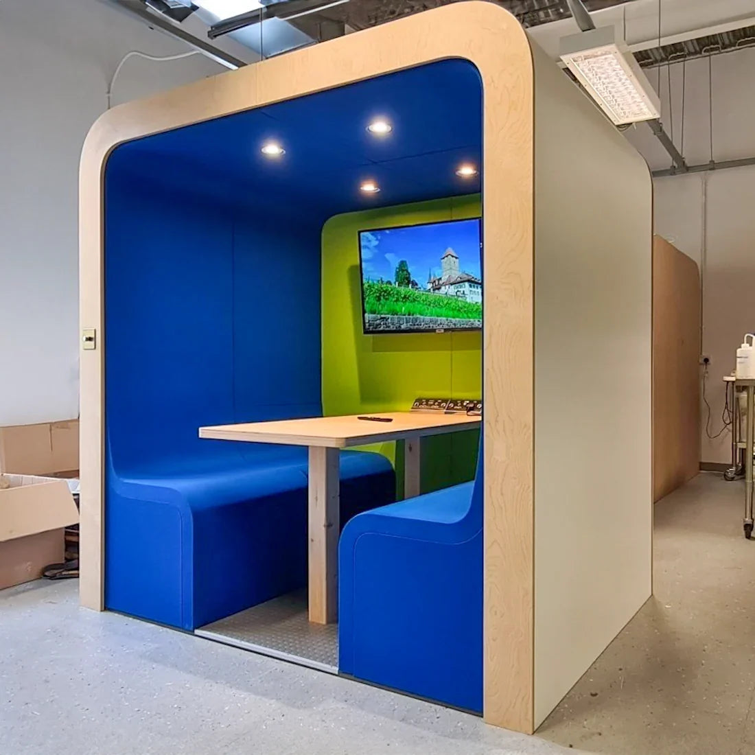 Dapapod four-person meeting pod with blue and green seating, table and integrated screen