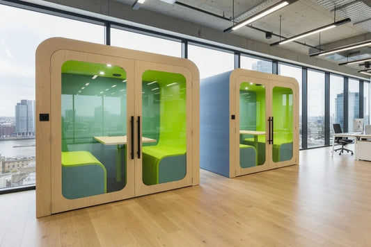 Two green Dapapod office meeting pods in a modern workspace with city views