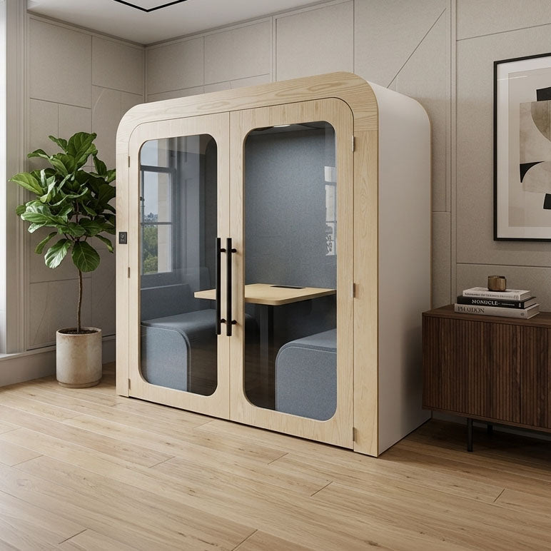 Modern office pod with glass walls in a room with a plant and books.