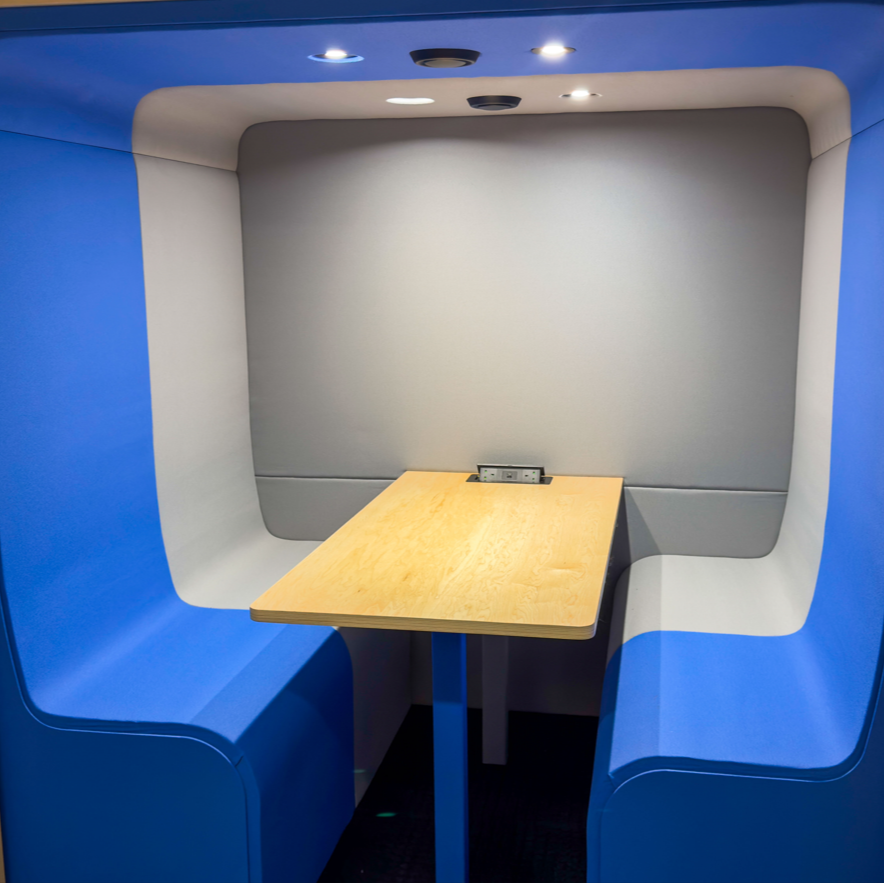 Inside a Dapapod meeting booth with blue wool seats and white surround
