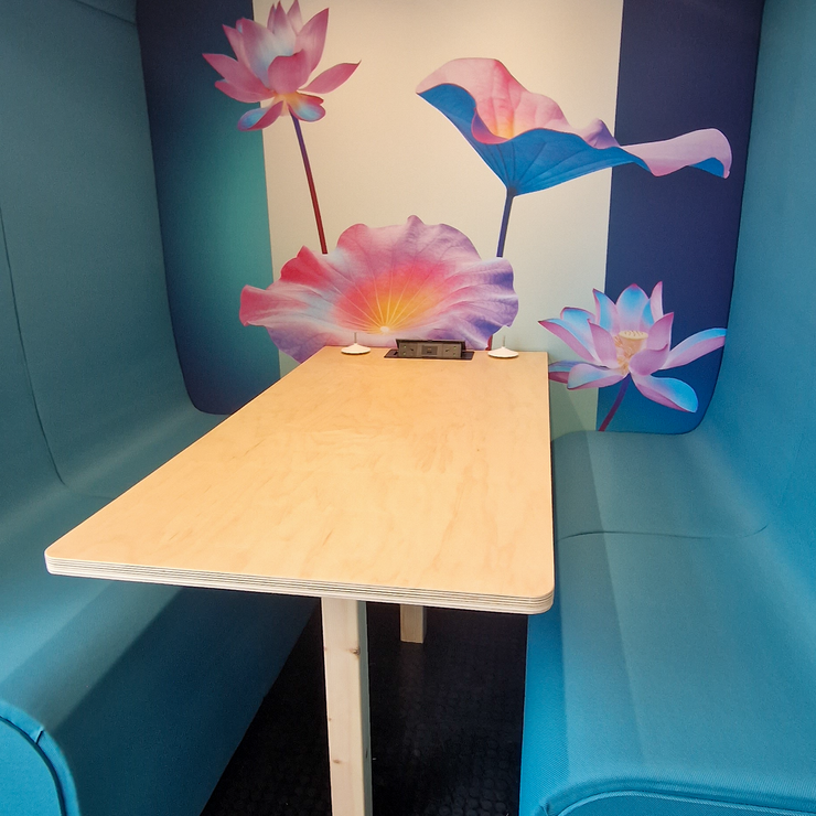 Inside a Dapapod booth with wall-mounted TV, desk and green wool interior