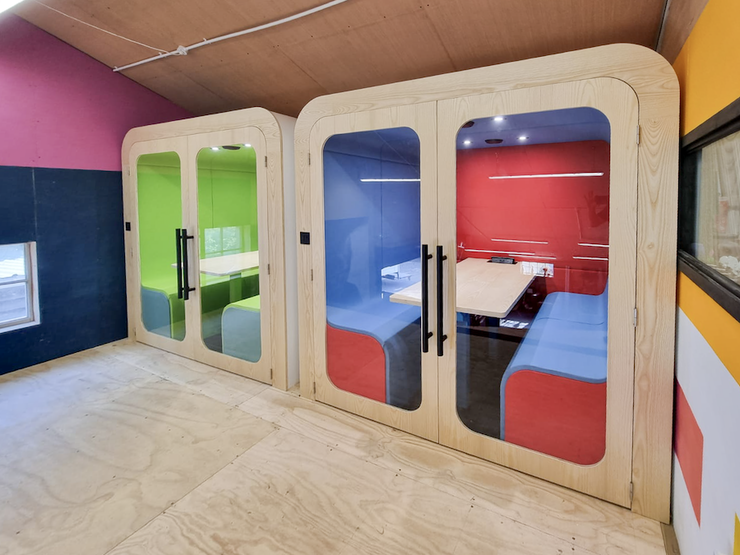 Two finished Dapapod meeting booths with green and red interiors in the Watford workshop