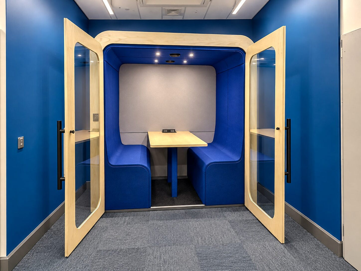 Dapapod four-person booth with blue wool interior and doors open against a blue wall