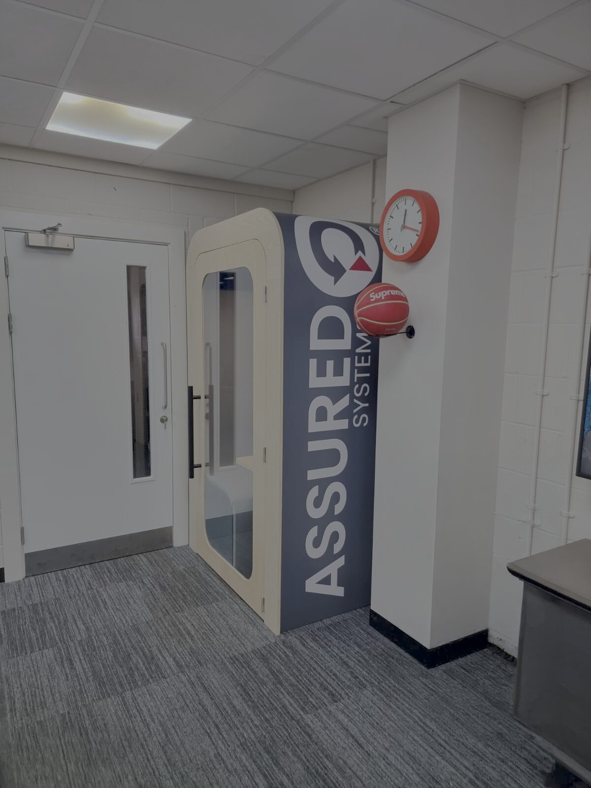Dapapod single pod with a branded wrap in a facility corridor