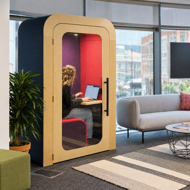Person working on a laptop inside a Dapapod single office pod with red and purple interior