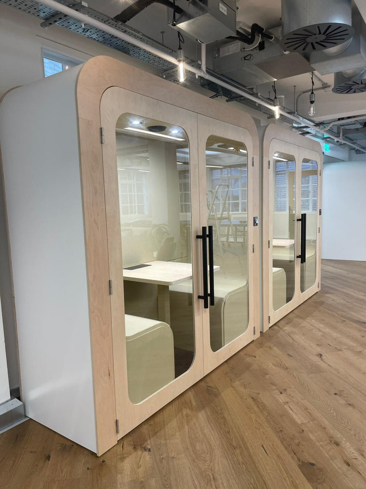 Two Dapapod meeting booths with cream wool interiors in an industrial-style office